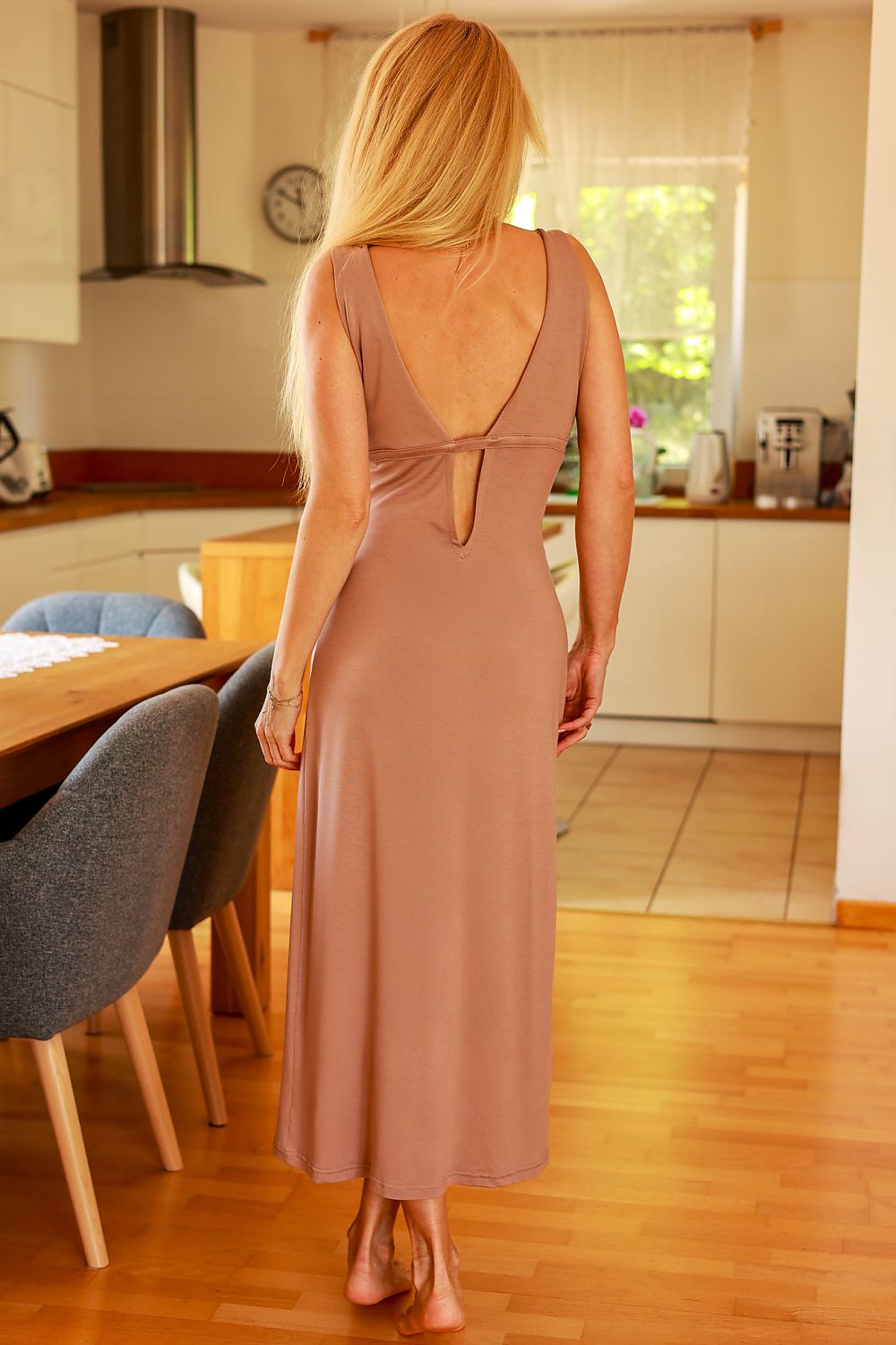 Woman in a long brown dress standing in a kitchen