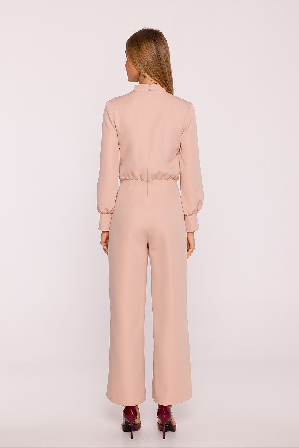 Woman wearing a light pink jumpsuit on a white background