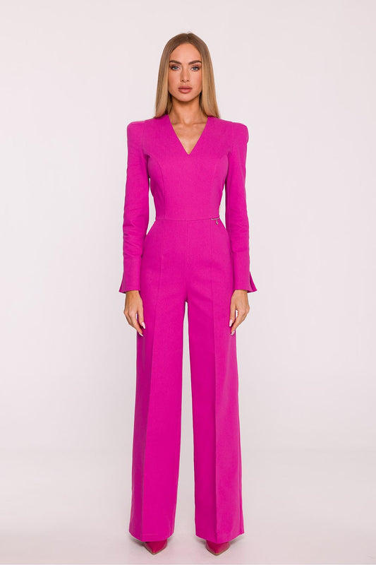 Woman wearing a bright pink jumpsuit on a light pink background
