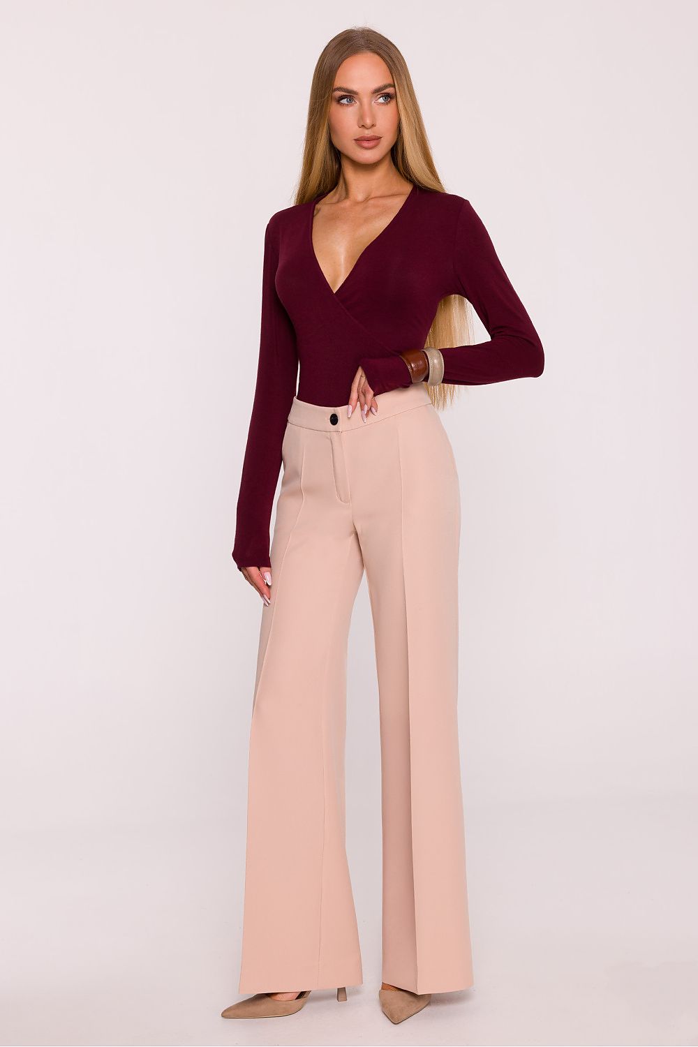 Woman wearing a burgundy top and beige pants on a white background