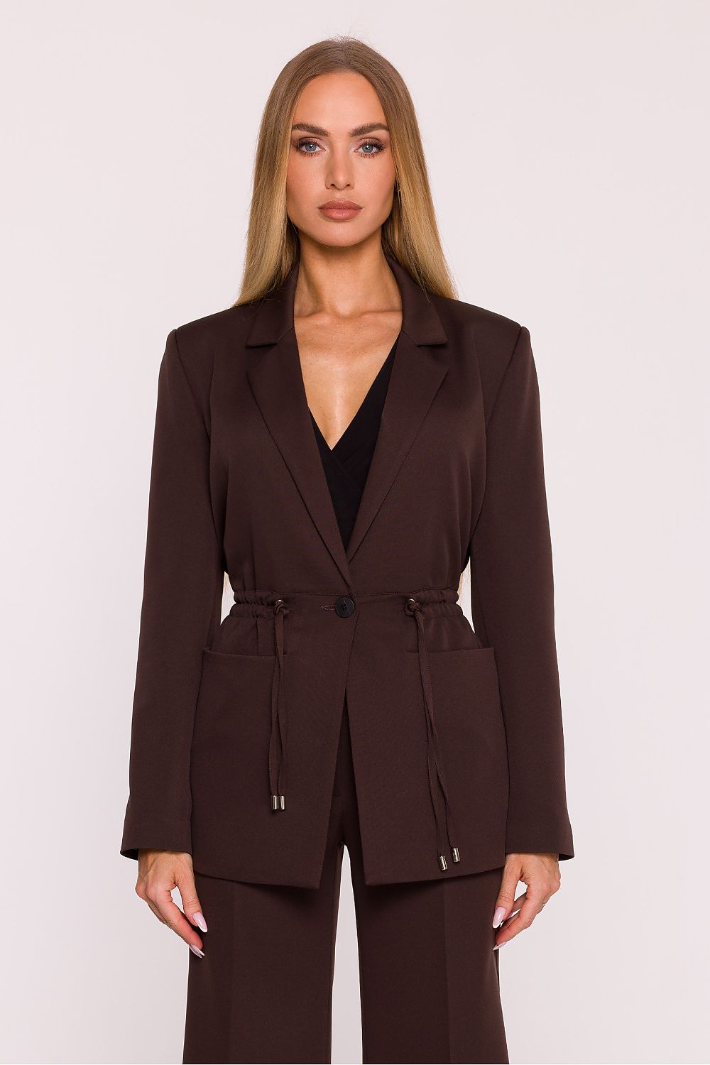 Woman wearing a brown suit against a white background