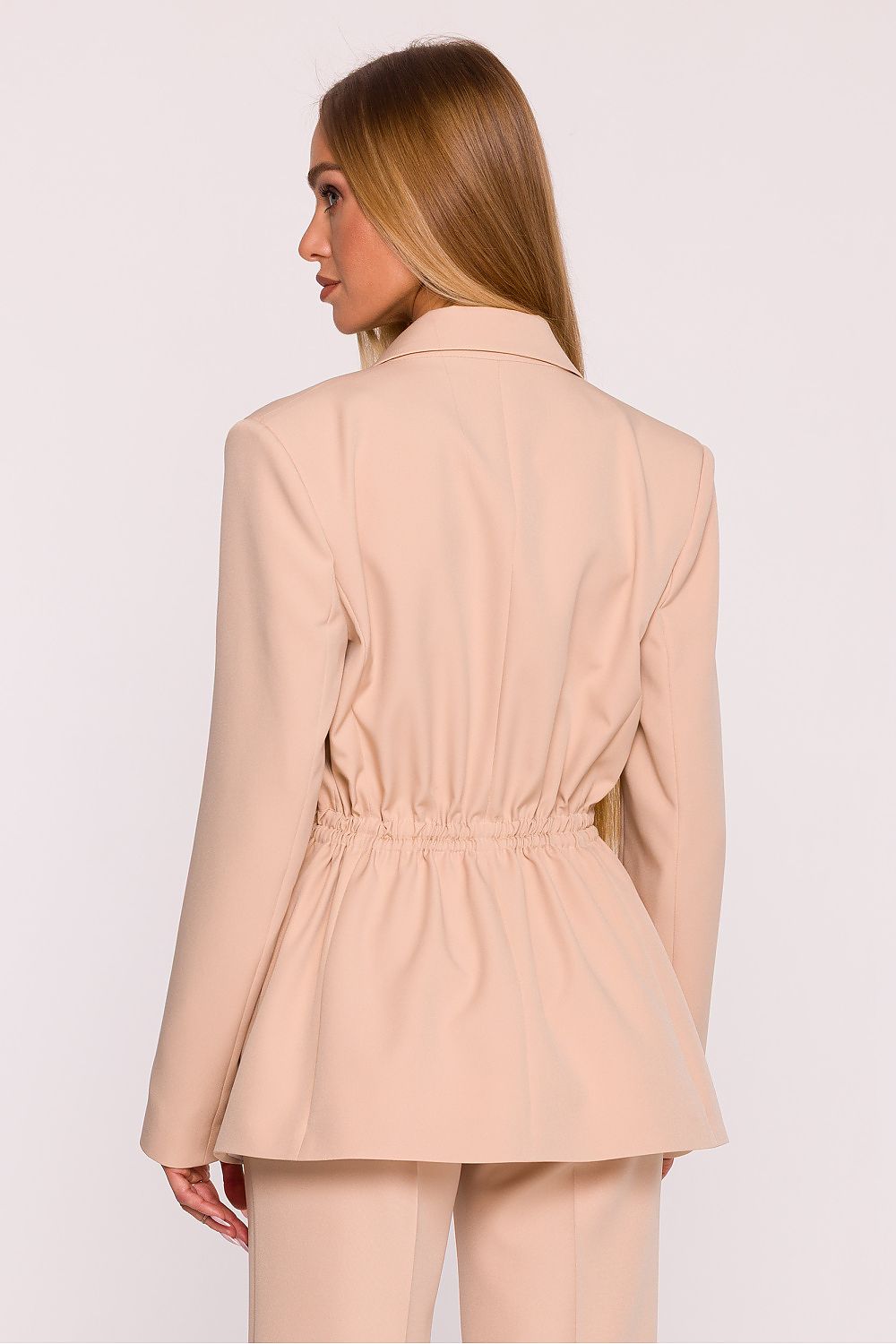 Woman wearing a beige blazer and pants on a white background