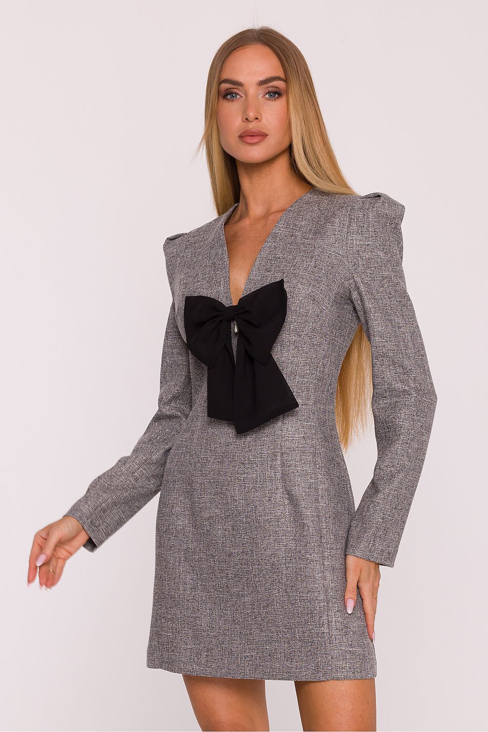 Woman wearing a gray dress with a black bow on a white background