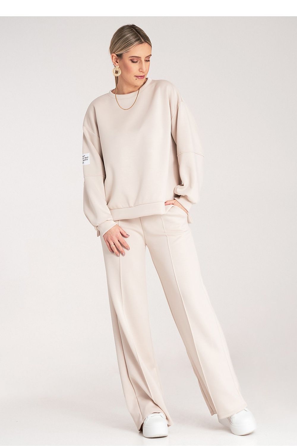 Woman wearing a beige outfit with a plain background