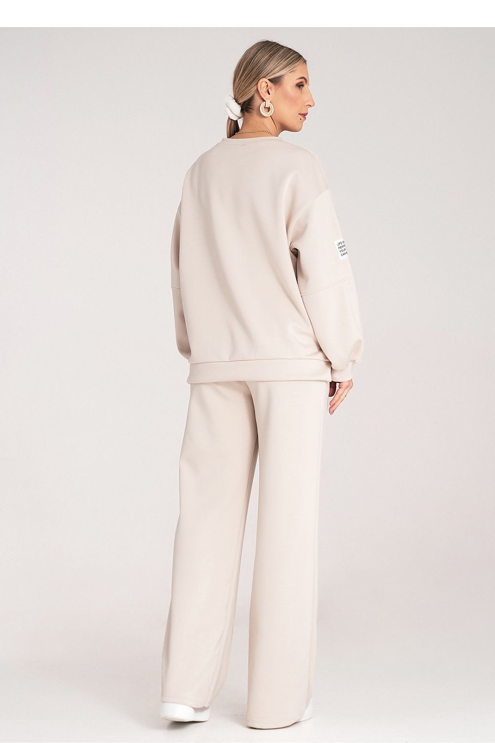 Woman wearing a beige tracksuit on a white background