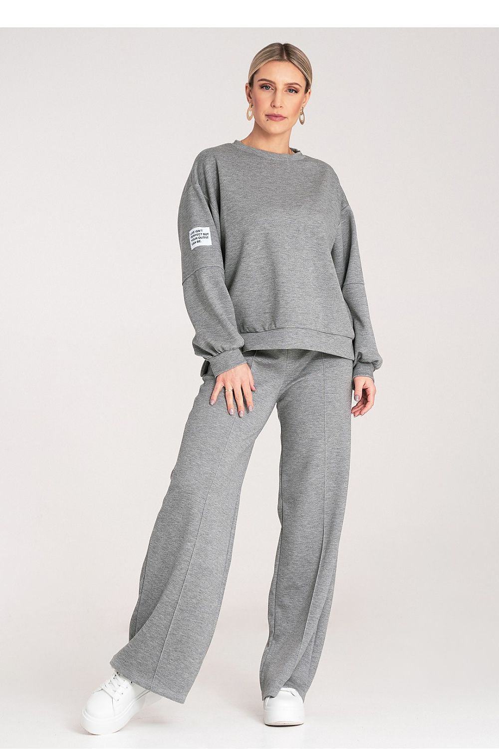 Woman wearing a gray sweatshirt and pants on a white background