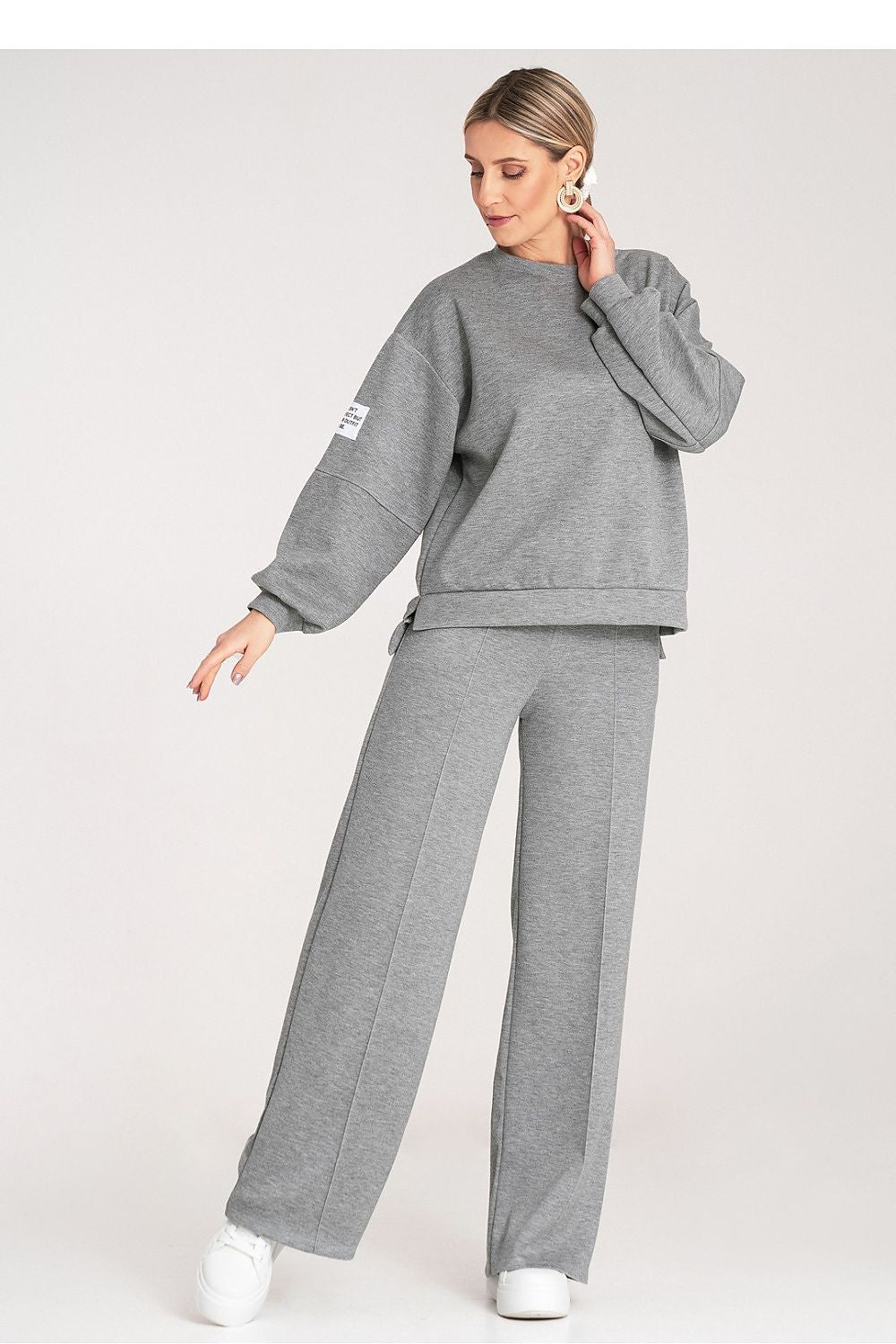 Woman wearing a gray tracksuit on a white background