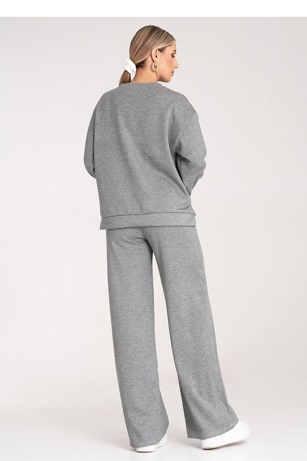 Person wearing a gray tracksuit on a white background