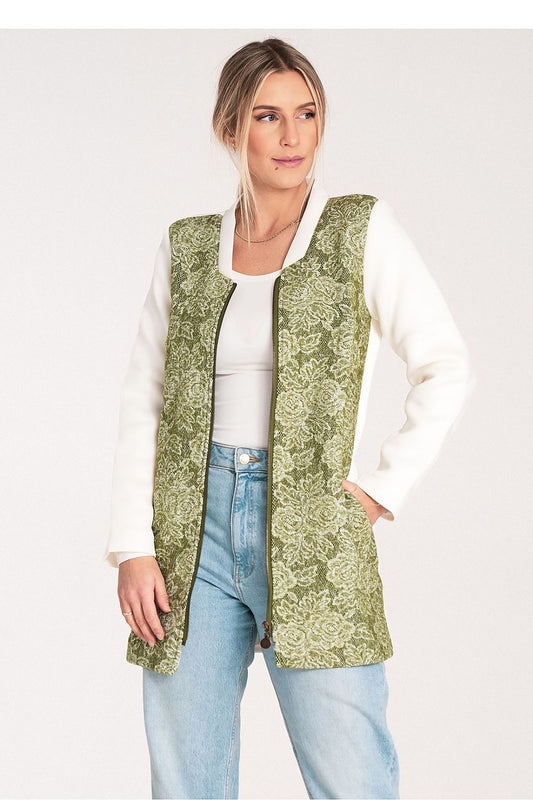 Woman wearing a green patterned vest over a white shirt and blue jeans on a white background