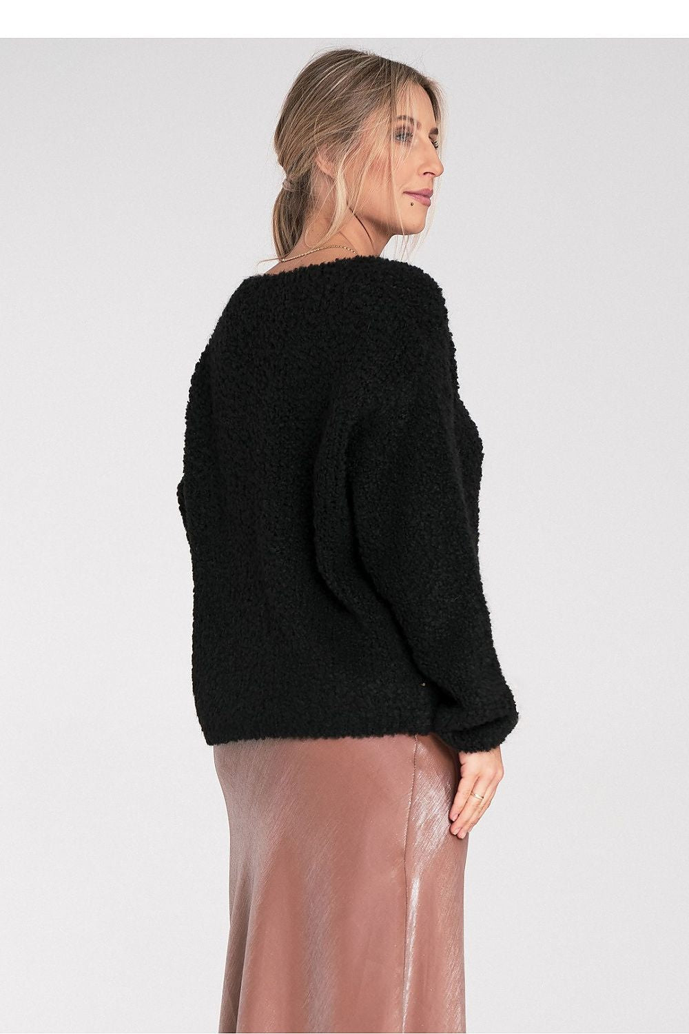 Woman wearing a black sweater on a light gray background