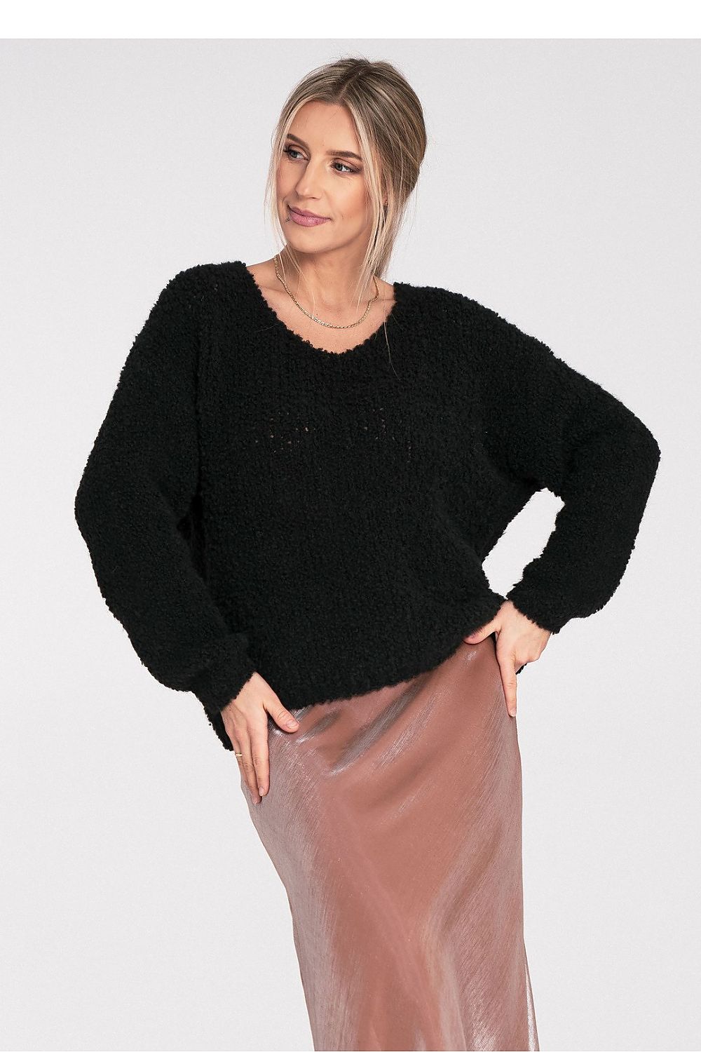 Woman wearing a black sweater and pink skirt on a white background