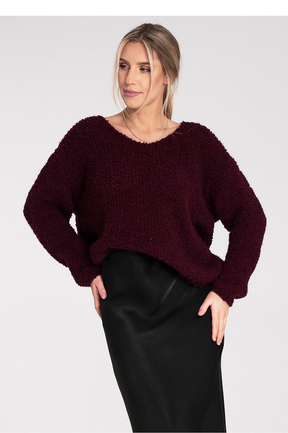 Woman wearing a burgundy sweater and black pants on a white background