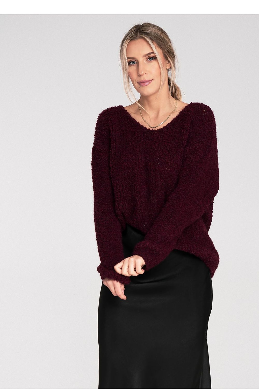 Woman wearing a burgundy sweater against a plain background