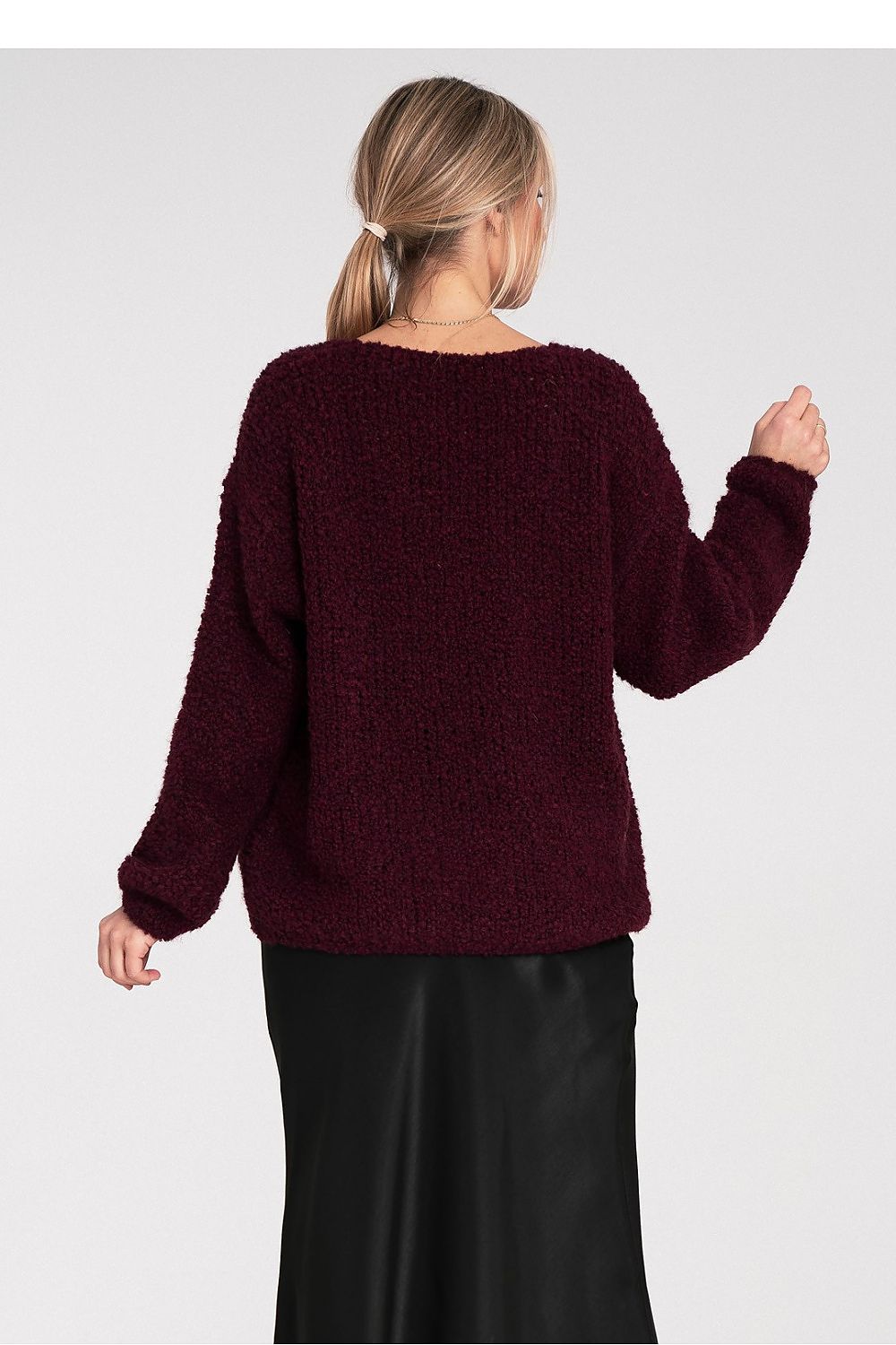 Person wearing a burgundy sweater against a plain background