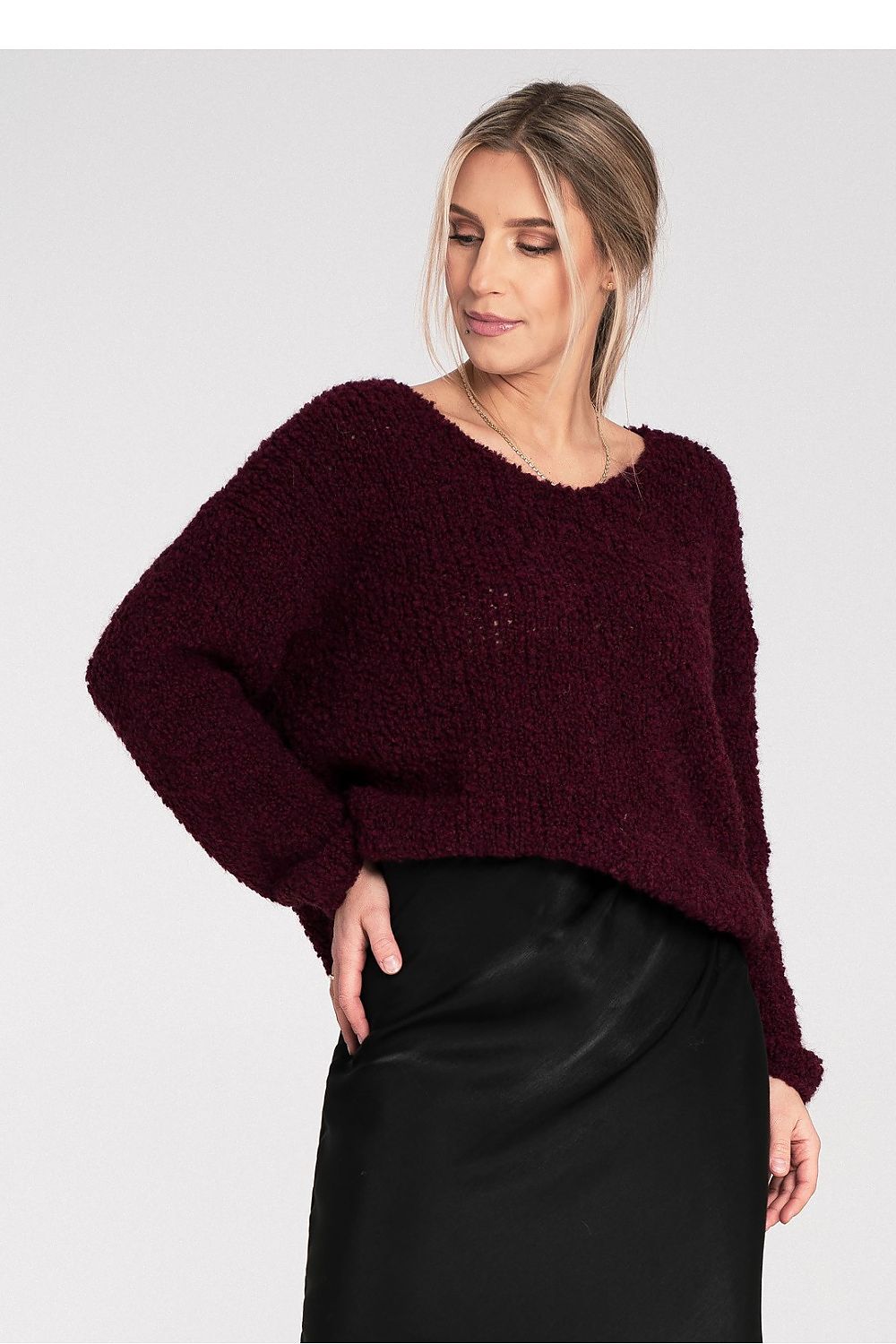 Woman wearing a burgundy sweater and black skirt on a white background