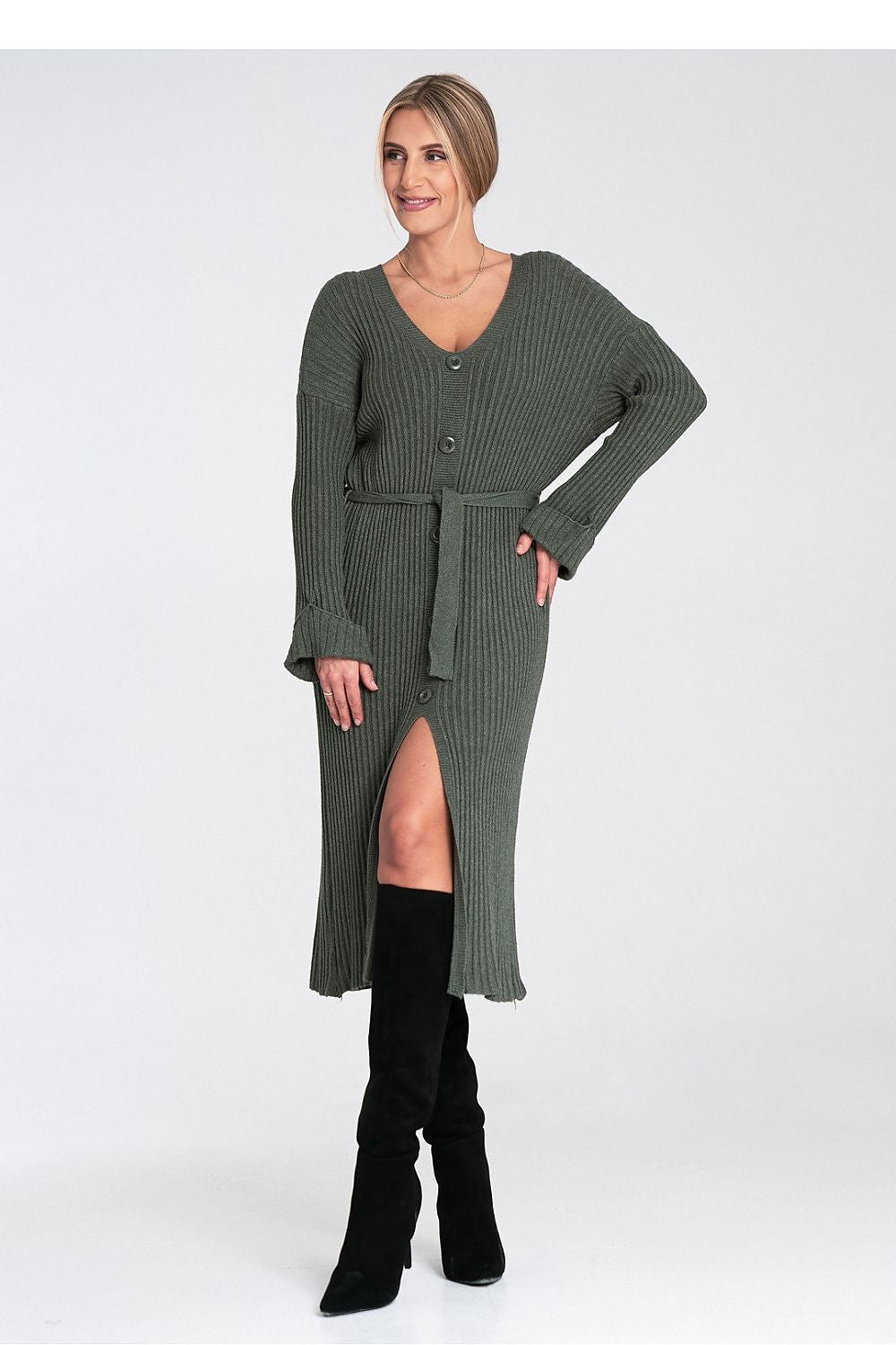 Woman wearing a green ribbed dress with a belt on a white background