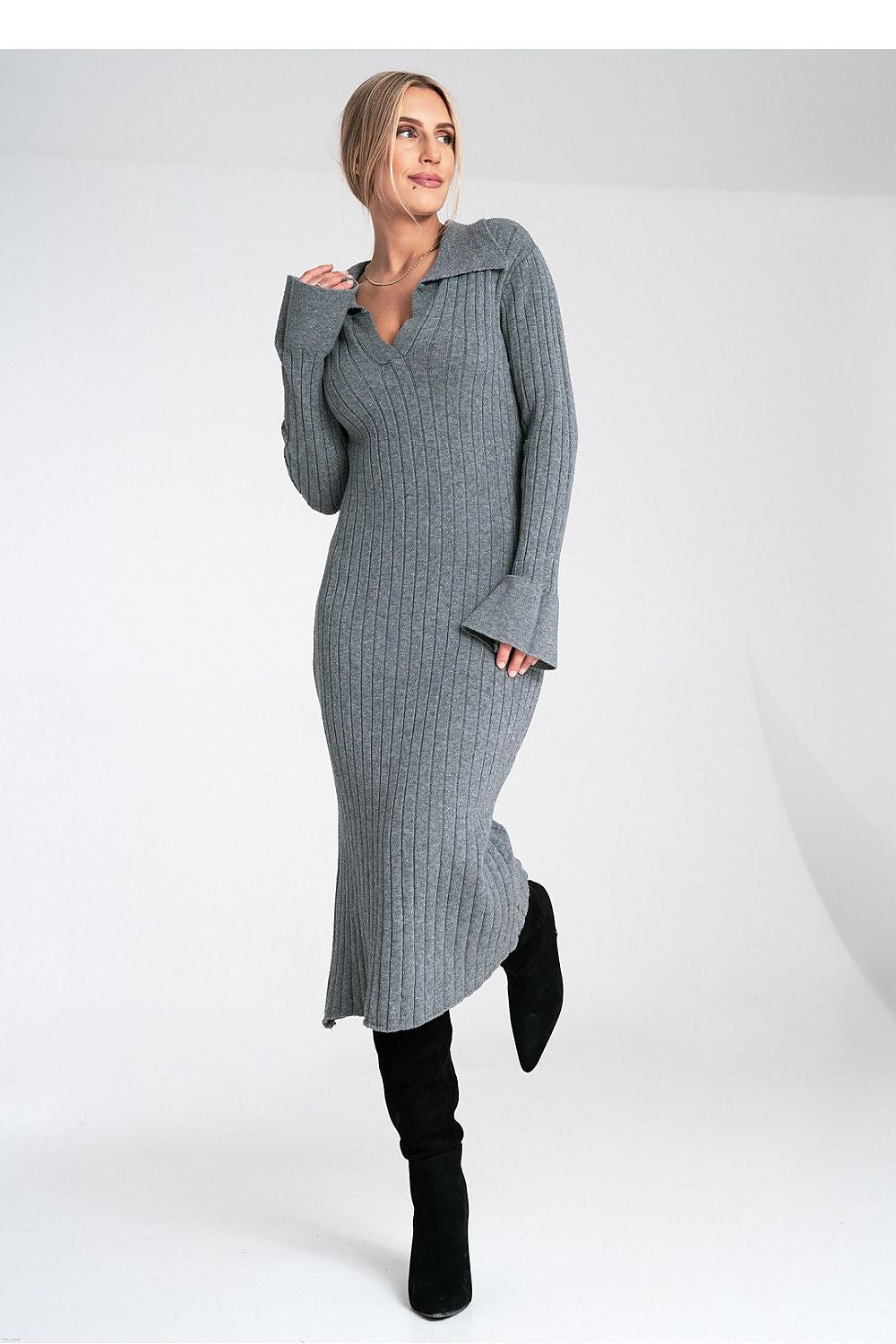 Woman wearing a gray ribbed dress with black boots on a white background