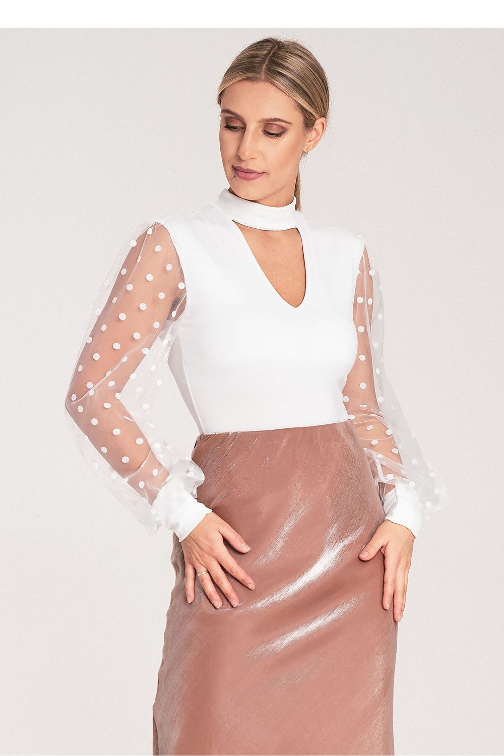 Woman wearing a white blouse with sheer sleeves and a brown skirt on a white background