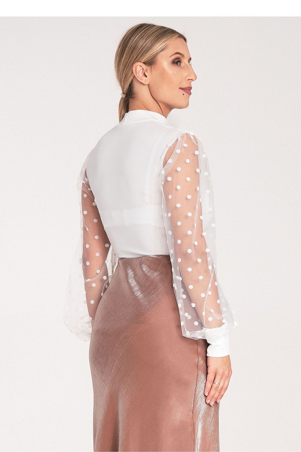 Woman wearing a white blouse with sheer sleeves and a brown skirt on a white background