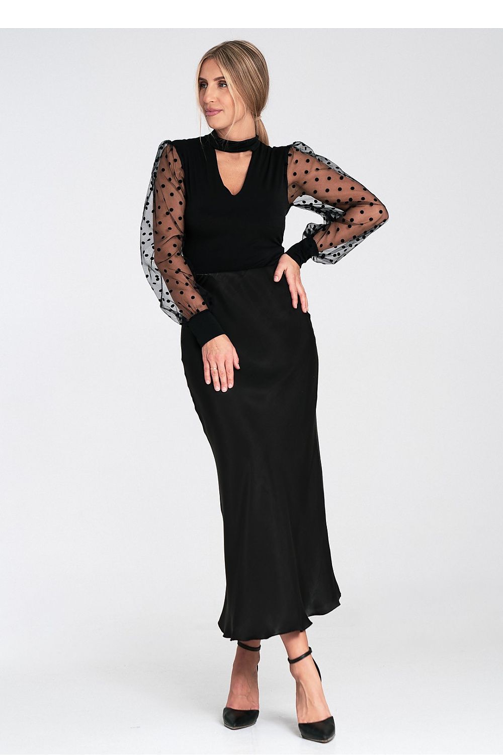 Woman wearing a black dress with sheer sleeves on a white background