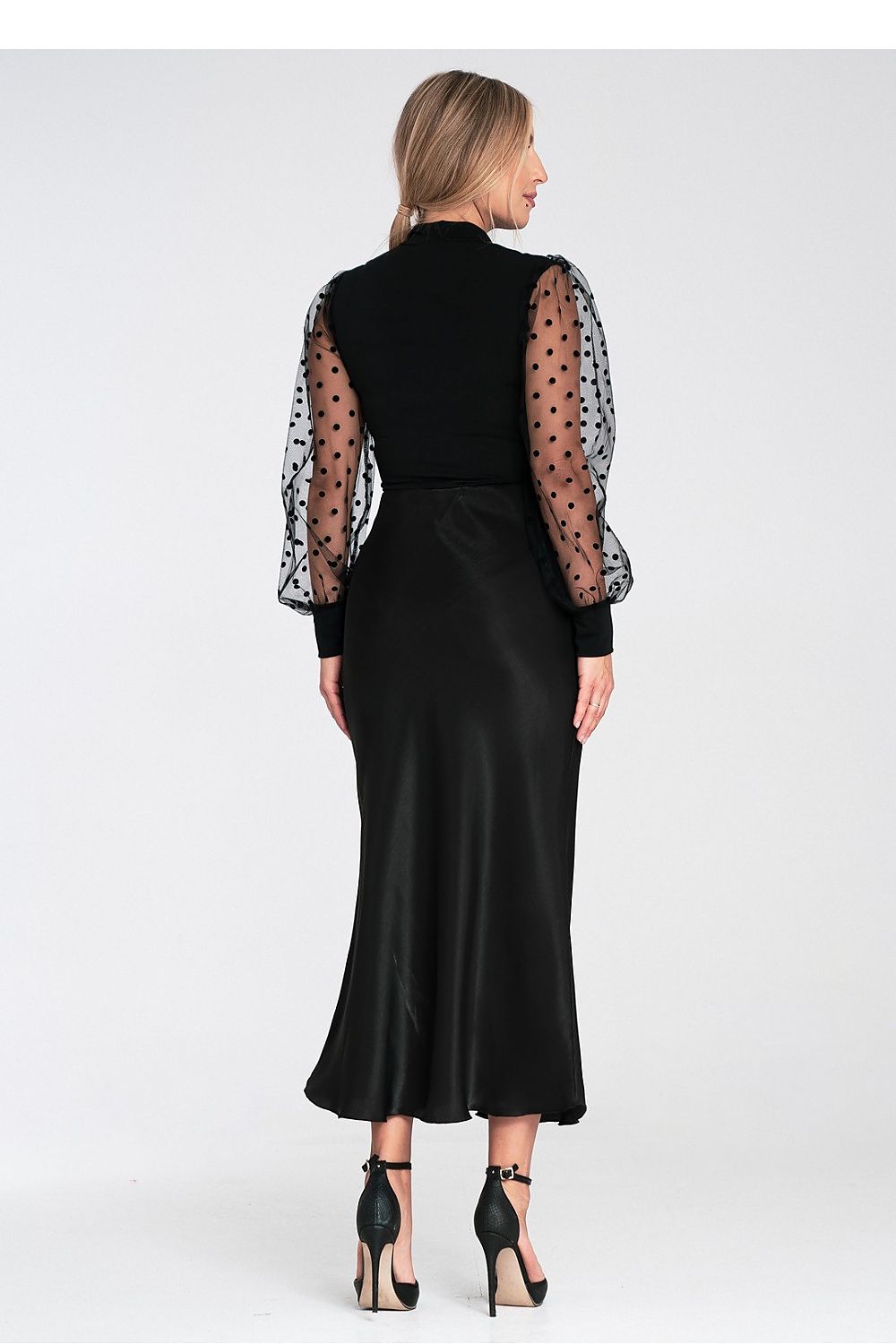 Woman wearing a black dress with sheer sleeves on a white background