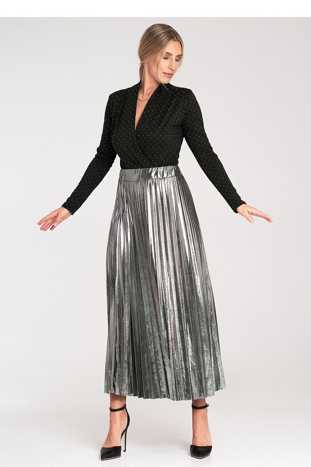 Woman wearing a black top and silver pleated skirt on a white background