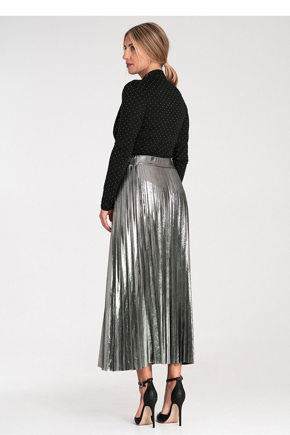 Woman wearing a black top and silver pleated skirt on a white background