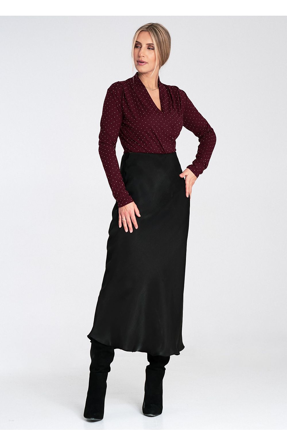 Woman wearing a burgundy top and black skirt on a white background