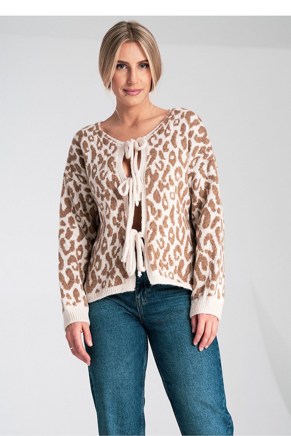 Woman wearing a leopard print cardigan with lace-up front on a plain background