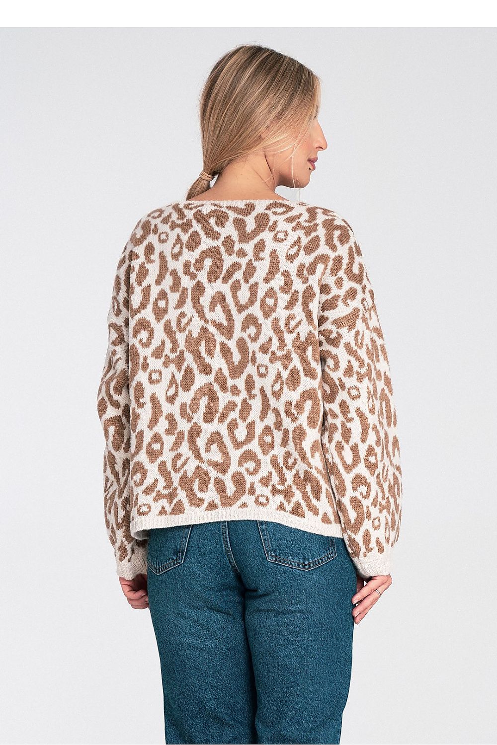 Woman wearing a leopard print top and blue jeans on a white background