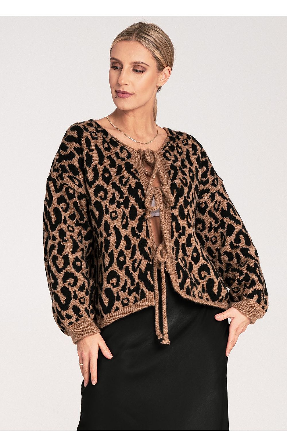 Woman wearing a leopard print sweater with a tie front on a white background