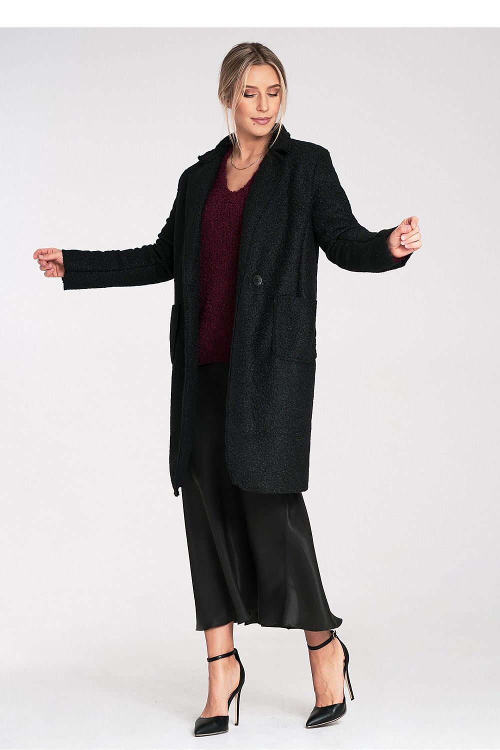 Woman wearing a black coat and black dress on a white background
