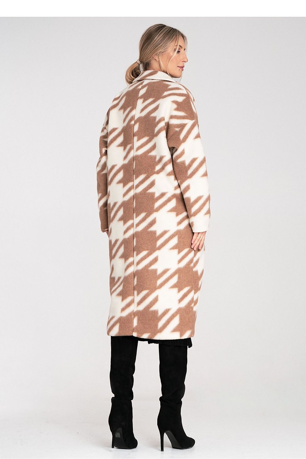 Woman wearing a long, patterned coat on a white background