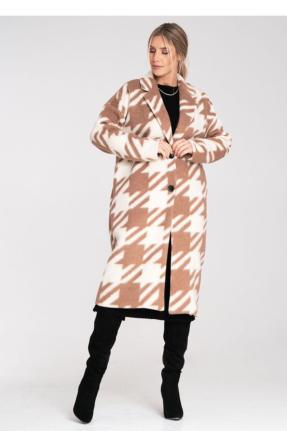 Woman wearing a long, patterned coat on a white background