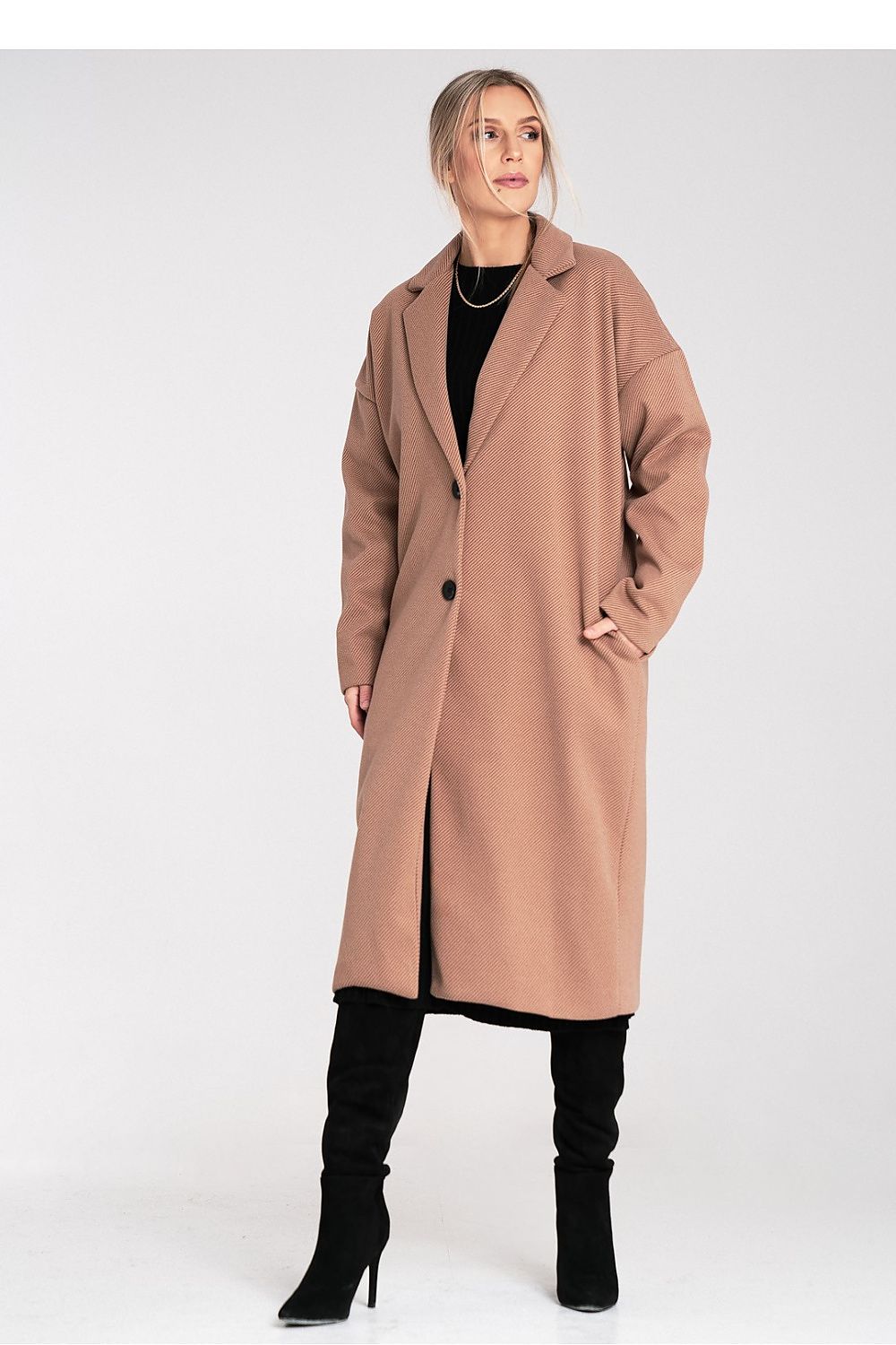 Woman wearing a long beige coat and black boots on a white background
