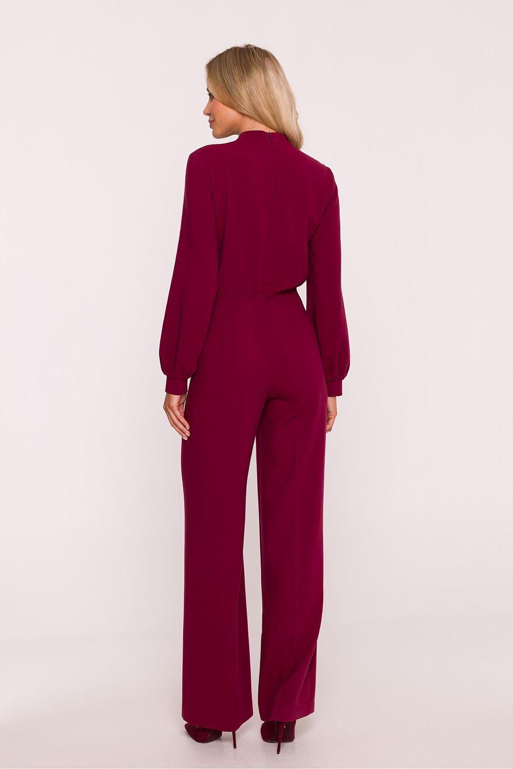 Woman wearing a burgundy jumpsuit on a white background