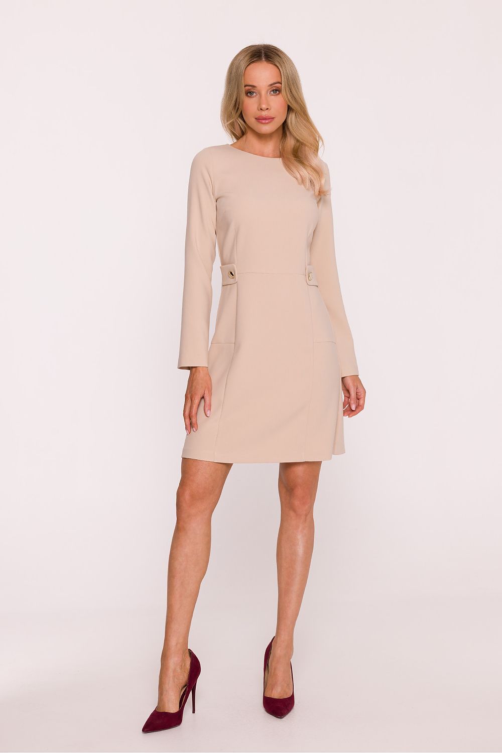 Woman wearing a beige dress with long sleeves on a white background
