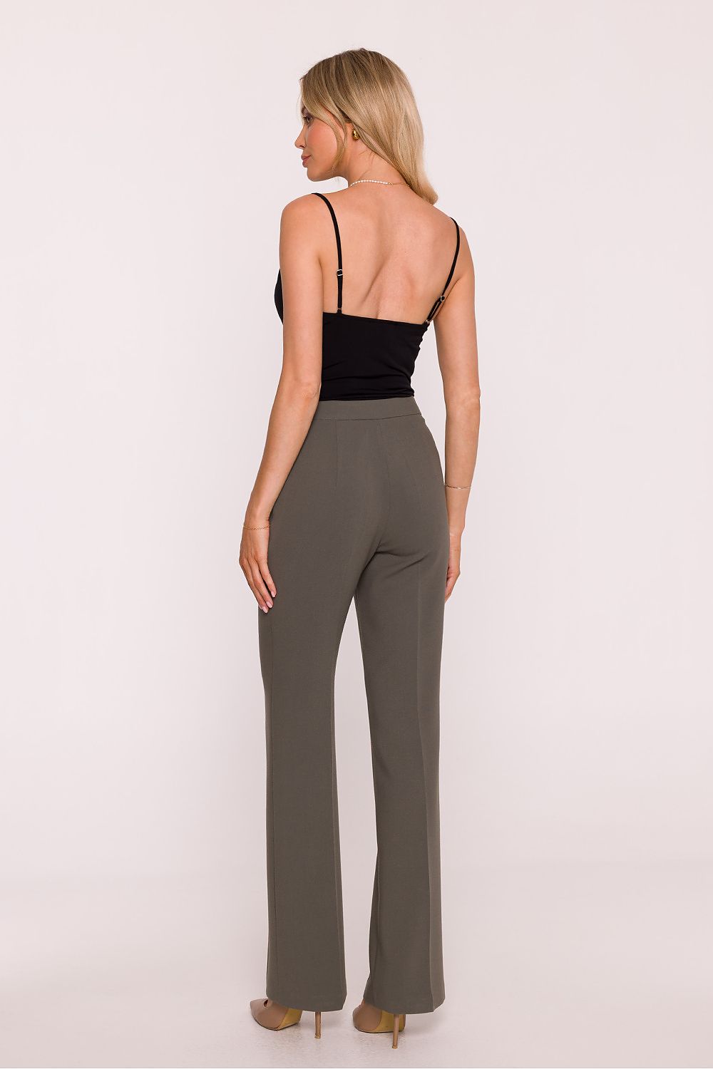 Woman wearing a black top and gray high-waisted pants on a white background
