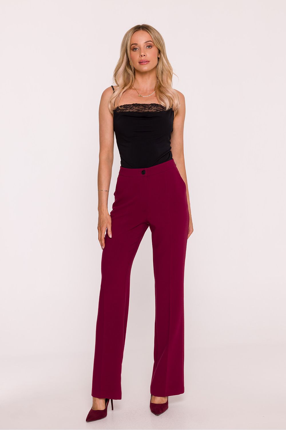 Woman wearing a black top and burgundy pants on a white background