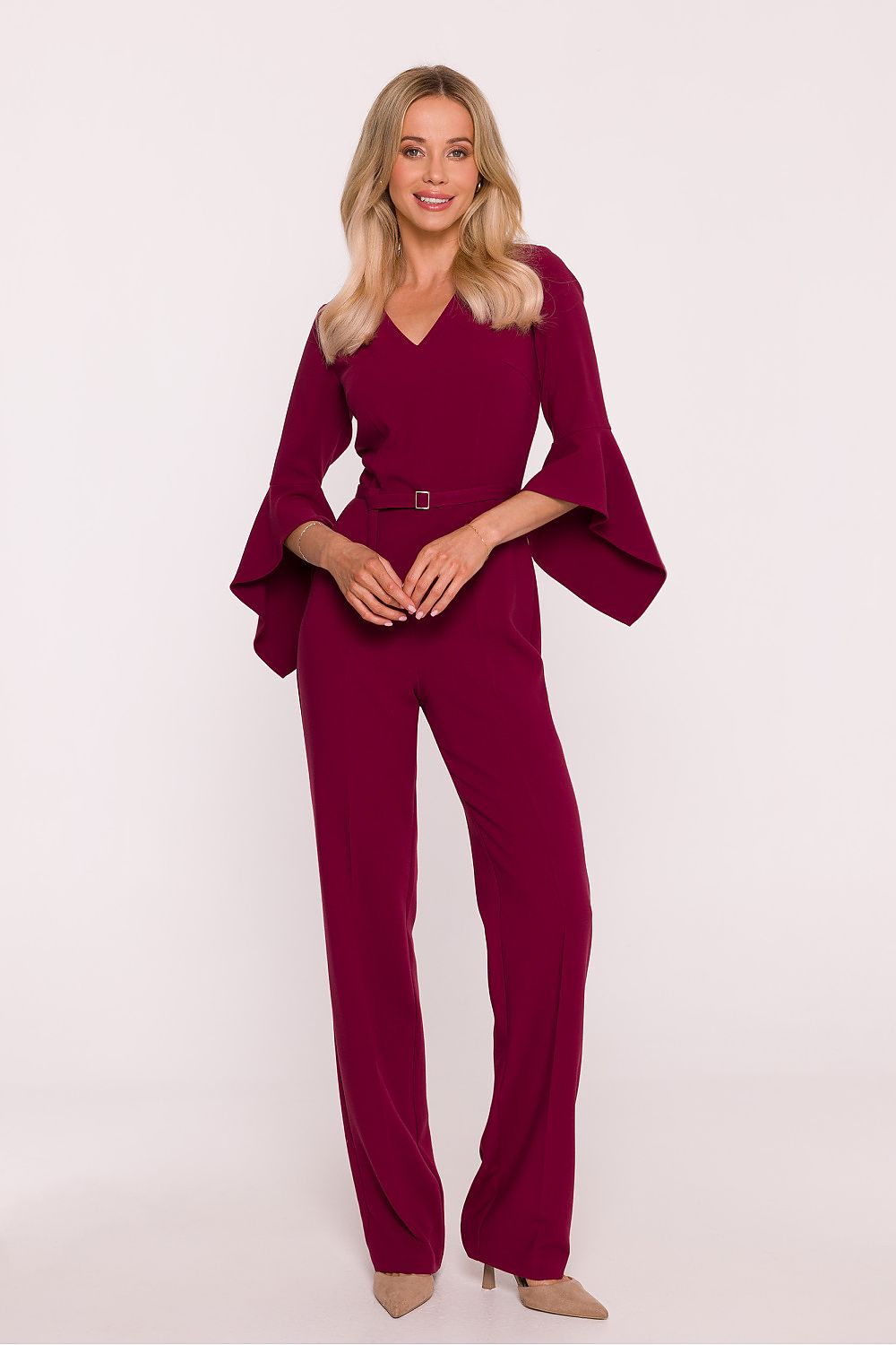 Woman wearing a burgundy jumpsuit with bell sleeves on a white background