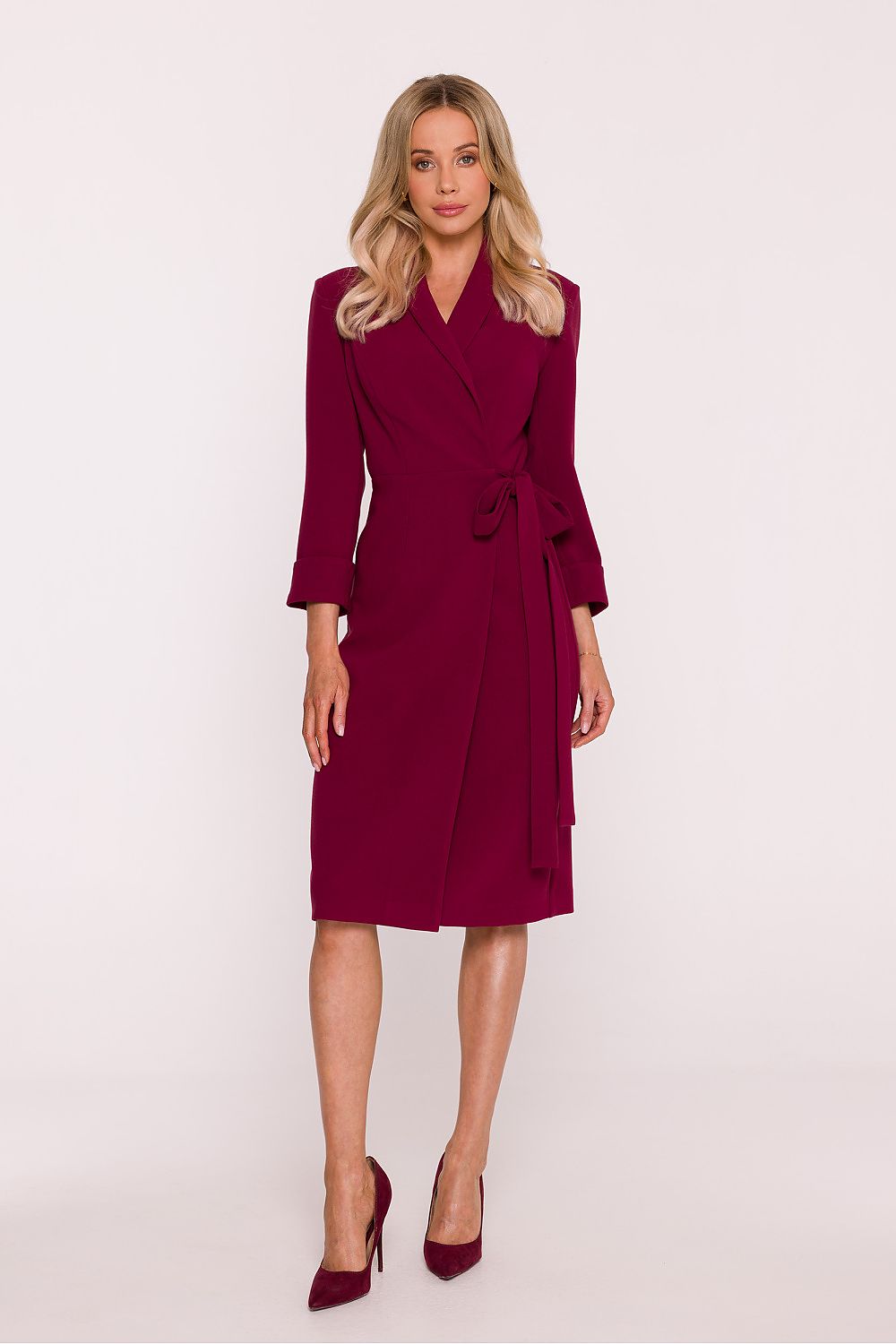 Woman wearing a burgundy dress with a belt on a white background
