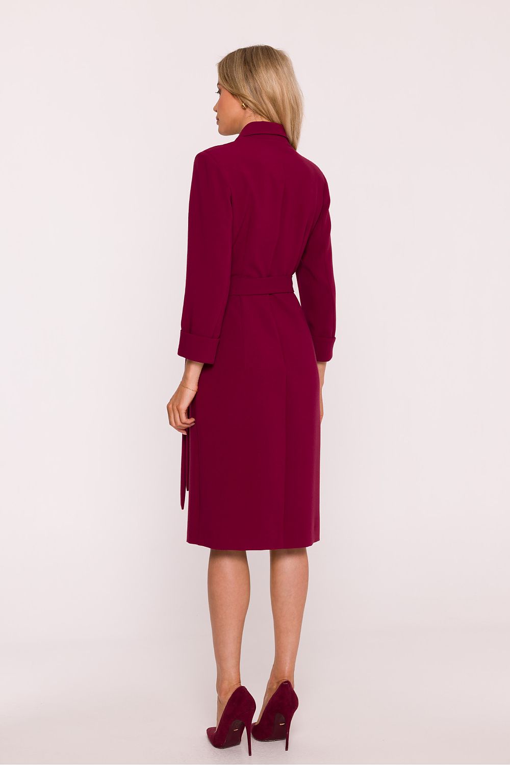 Woman wearing a burgundy dress with a belt on a white background