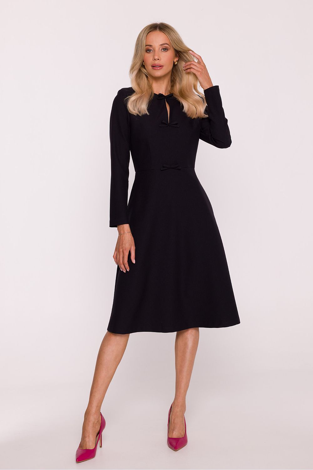 Woman wearing a black dress with long sleeves on a white background