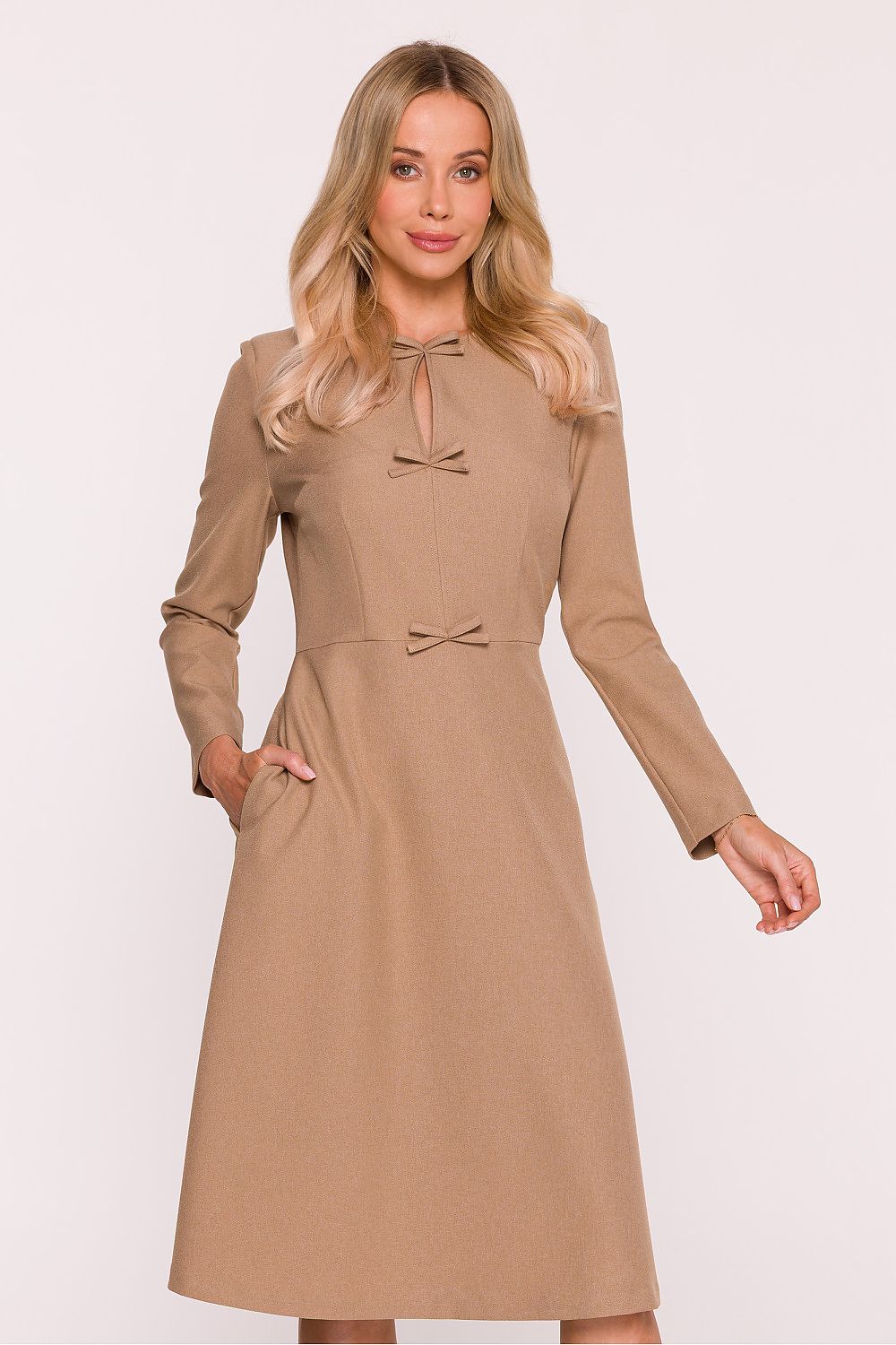 Woman wearing a beige dress with long sleeves on a white background