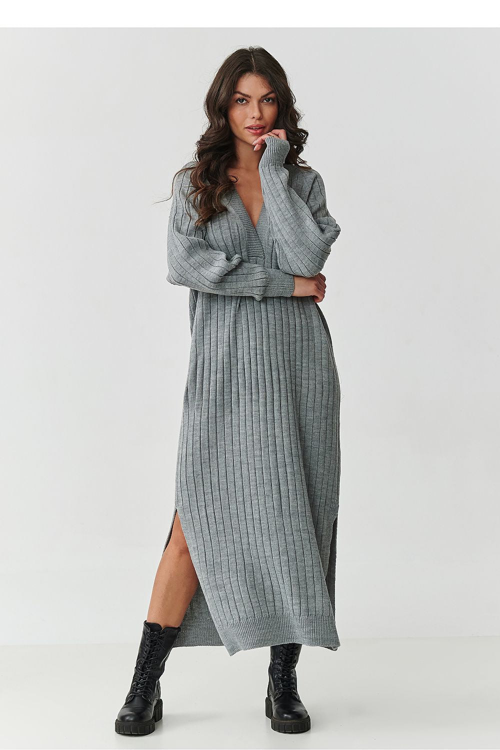Woman wearing a gray ribbed dress with a slit on a white background