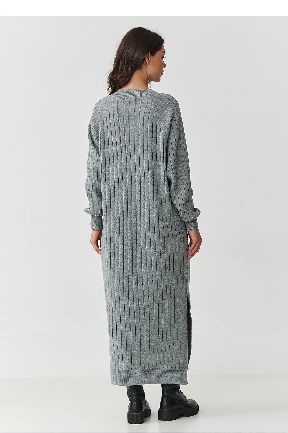 Woman wearing a long gray ribbed dress on a white background