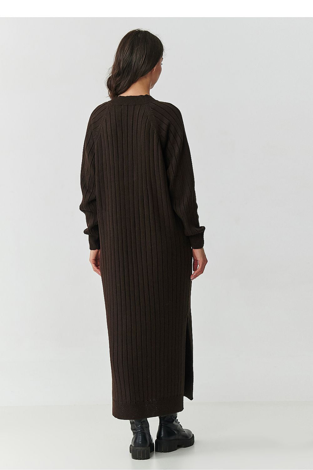 Woman wearing a long black ribbed dress on a white background