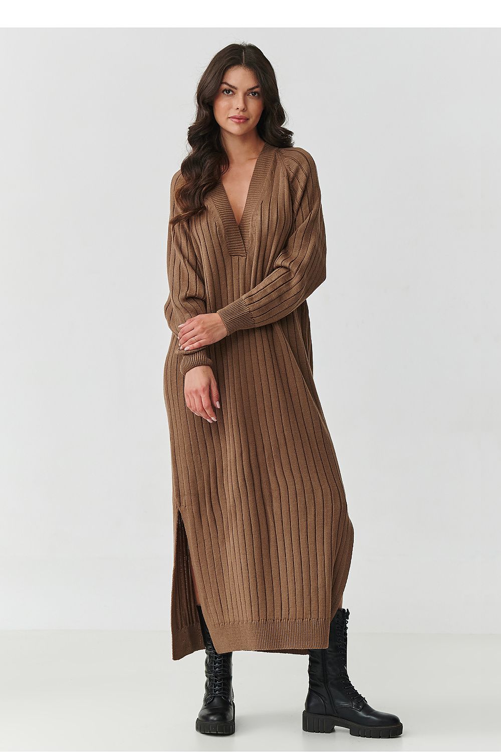 Woman wearing a long brown ribbed dress on a white background