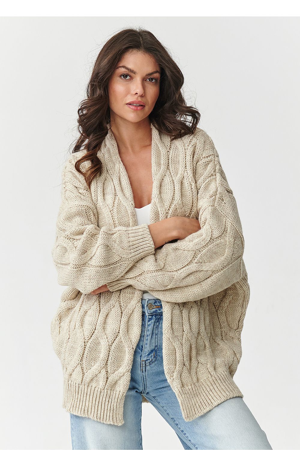 Woman wearing a beige cable knit cardigan on a white background