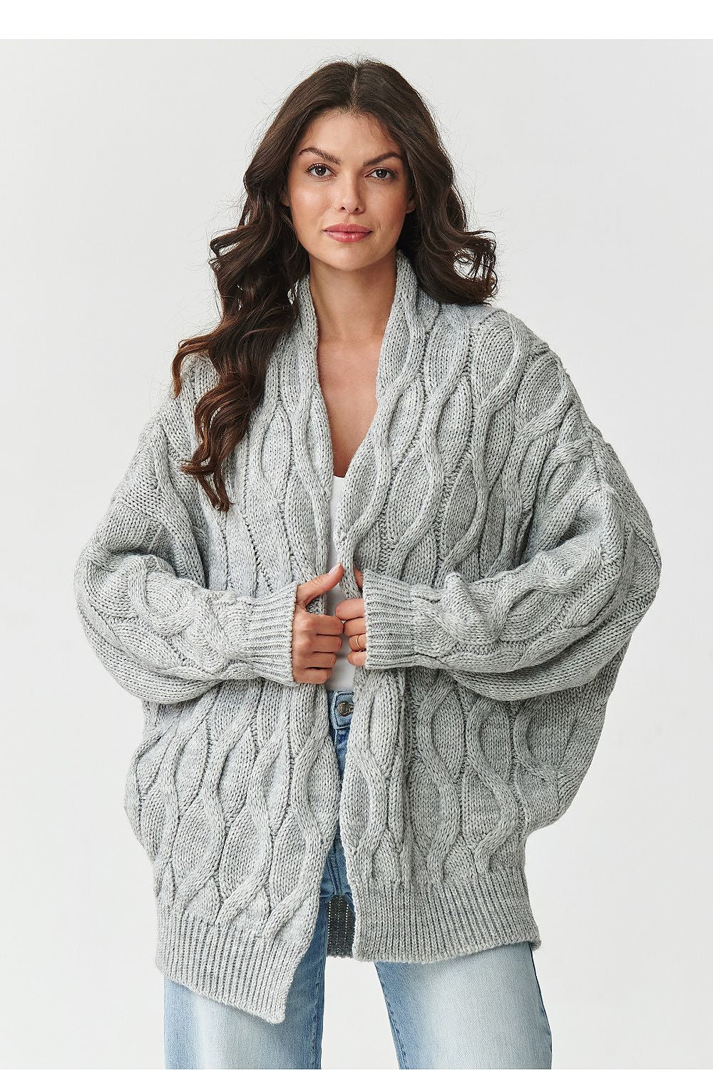 Woman wearing a gray cable knit cardigan on a white background